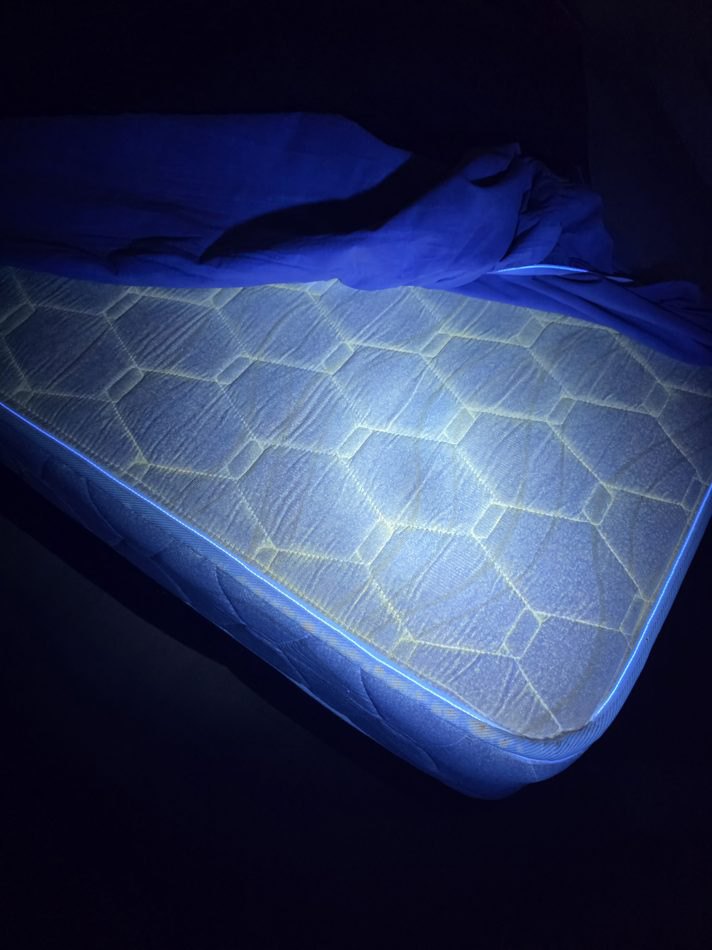 The mattress in the Bangsar holiday home under ultraviolet light, the quilted surface fluorescing edge to edge